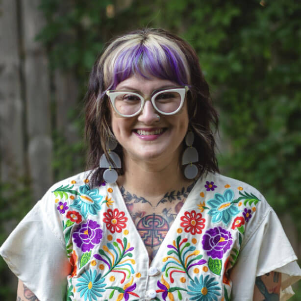 A photo of Rosa Ellenberger, MS, LPC smiling outdoors and wearing a colorful floral shirt